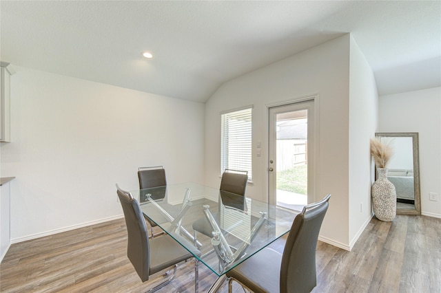 dining area featuring vaulted ceiling and light wood-type flooring