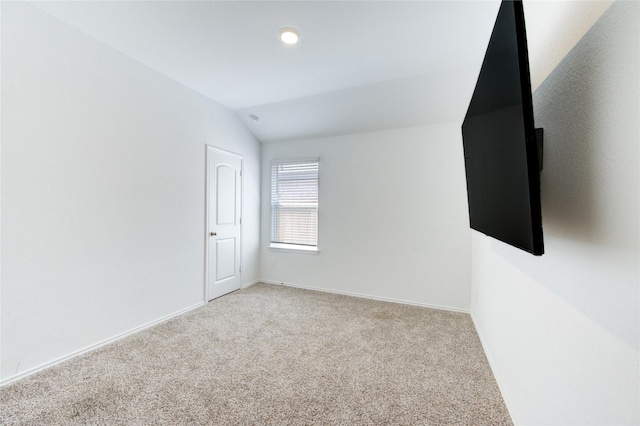 carpeted empty room featuring vaulted ceiling