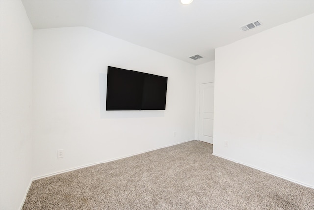 spare room featuring light carpet and vaulted ceiling