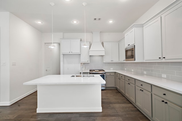 kitchen featuring pendant lighting, sink, custom exhaust hood, a kitchen island with sink, and stainless steel appliances