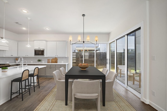 dining room with an inviting chandelier, a wealth of natural light, and dark hardwood / wood-style floors