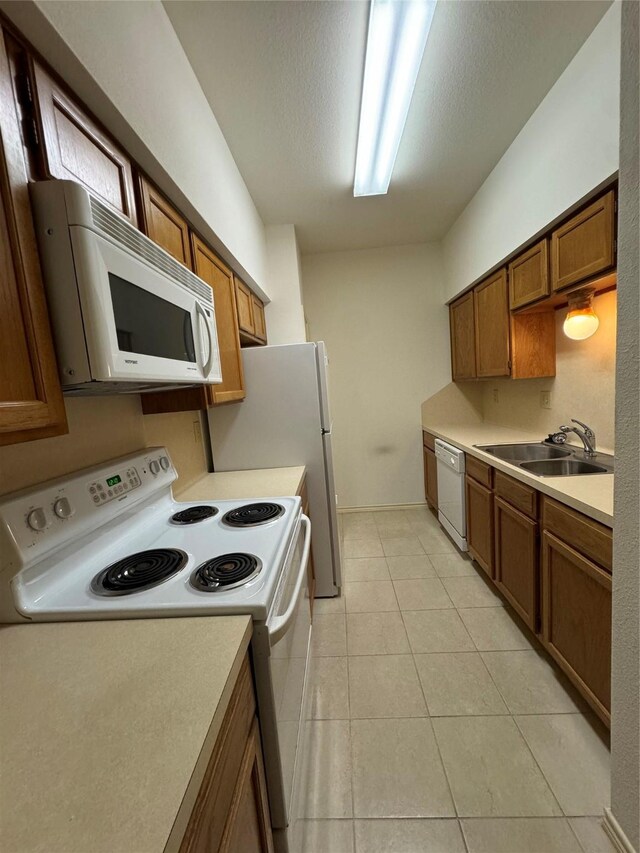 kitchen with sink, white appliances, light tile patterned floors, and a textured ceiling