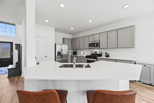 kitchen featuring stainless steel appliances, a kitchen bar, sink, and light hardwood / wood-style flooring