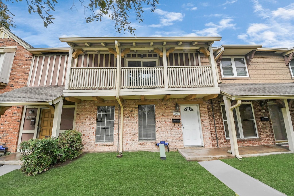 multi unit property featuring a front lawn and a balcony