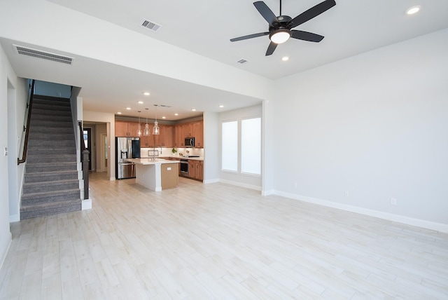 unfurnished living room featuring ceiling fan, sink, and light hardwood / wood-style floors