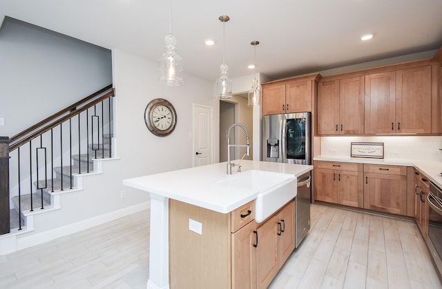 kitchen with sink, appliances with stainless steel finishes, hanging light fixtures, a center island with sink, and decorative backsplash