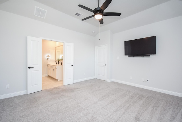 unfurnished bedroom featuring lofted ceiling, light colored carpet, ceiling fan, and ensuite bathroom