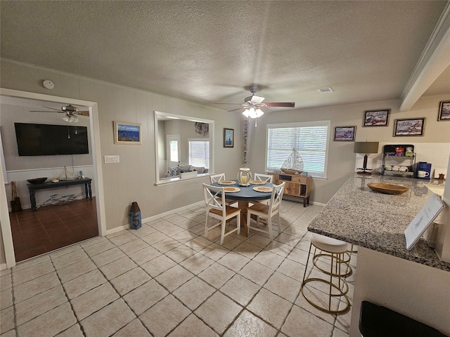 tiled dining room with a textured ceiling, plenty of natural light, and ceiling fan