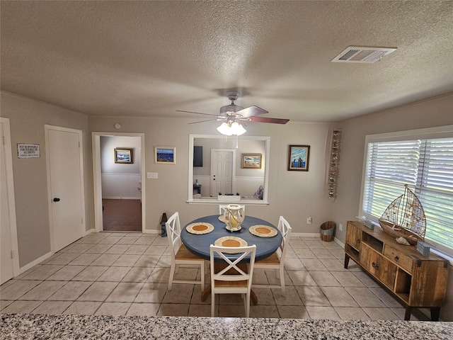 tiled dining space with a textured ceiling and ceiling fan