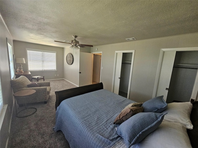 bedroom featuring carpet, two closets, a textured ceiling, and ceiling fan