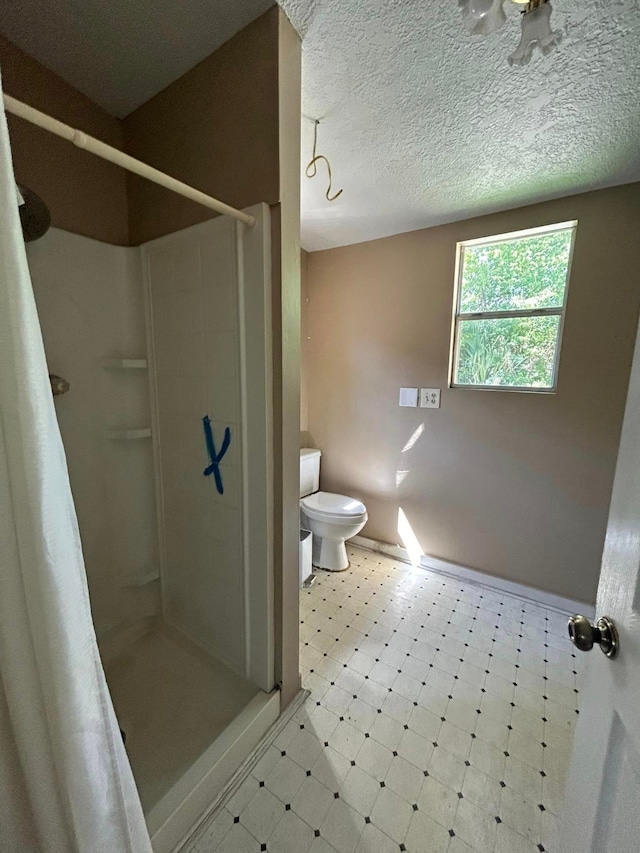 bathroom with a shower with curtain, toilet, and a textured ceiling