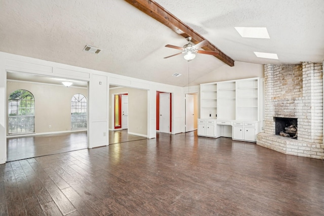 unfurnished living room featuring vaulted ceiling with skylight, a fireplace, ceiling fan, dark wood-type flooring, and a textured ceiling