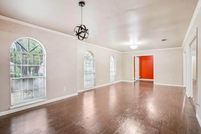 spare room with dark wood-type flooring, ornamental molding, an inviting chandelier, and a wealth of natural light