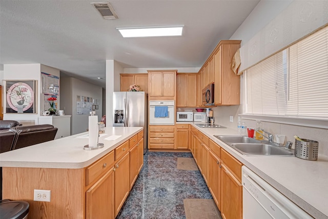 kitchen featuring stainless steel appliances, a center island, sink, and light brown cabinets