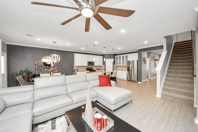 living room featuring crown molding, ceiling fan with notable chandelier, and light hardwood / wood-style flooring