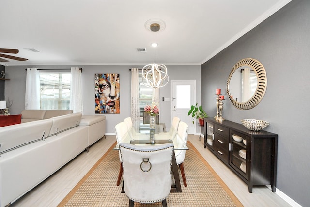 dining area with ceiling fan with notable chandelier, ornamental molding, and light hardwood / wood-style floors