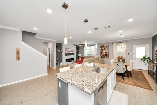 kitchen featuring pendant lighting, sink, a high end fireplace, an island with sink, and stainless steel dishwasher