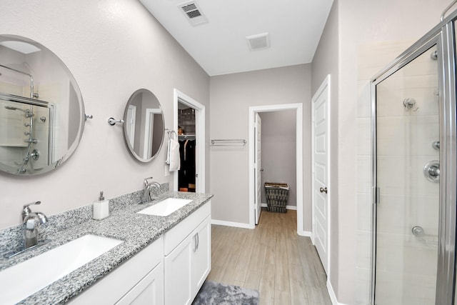 bathroom with vanity, a shower with shower door, and wood-type flooring