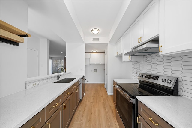 kitchen with appliances with stainless steel finishes, sink, white cabinets, backsplash, and light stone countertops