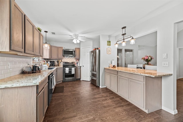 kitchen featuring light stone counters, appliances with stainless steel finishes, and hanging light fixtures