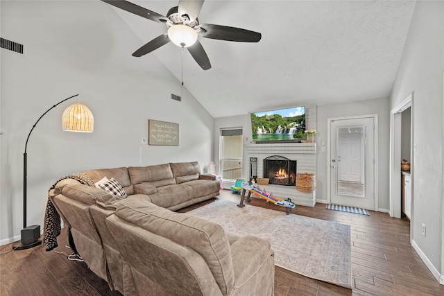 living room featuring vaulted ceiling, a brick fireplace, dark hardwood / wood-style floors, and ceiling fan