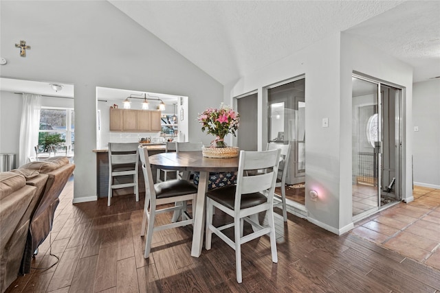 dining room featuring dark hardwood / wood-style flooring, high vaulted ceiling, and a textured ceiling