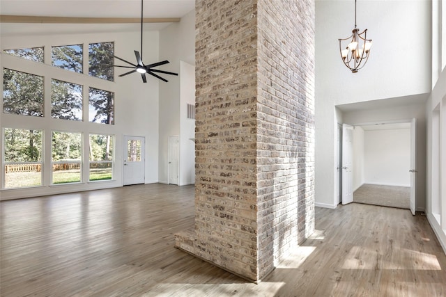 interior space with a high ceiling, wood-type flooring, and ceiling fan with notable chandelier