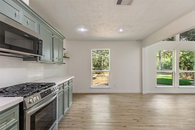 kitchen with decorative backsplash, stainless steel appliances, a textured ceiling, and light wood-type flooring