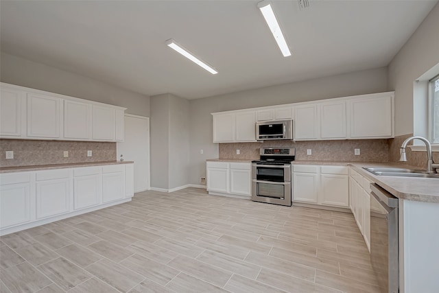 kitchen with backsplash, stainless steel appliances, sink, and white cabinets