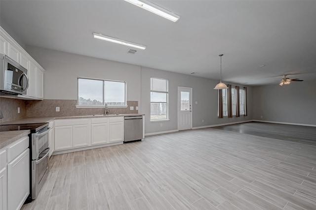 kitchen featuring sink, white cabinetry, light hardwood / wood-style flooring, stainless steel appliances, and decorative backsplash