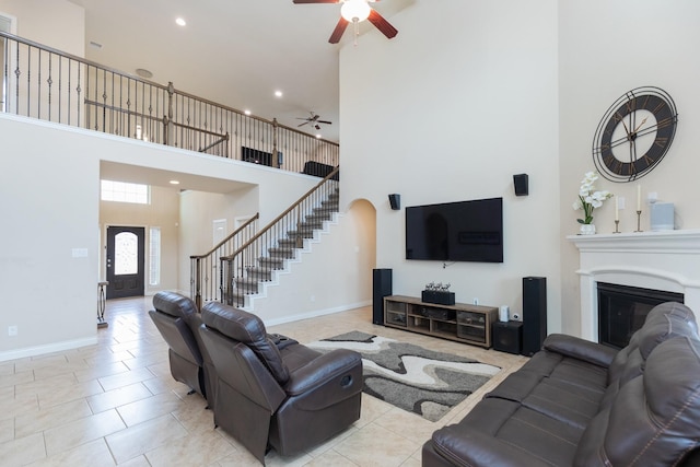 living room with a towering ceiling, light tile patterned floors, and ceiling fan