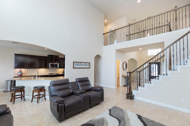 living room with sink, light tile patterned floors, and a high ceiling