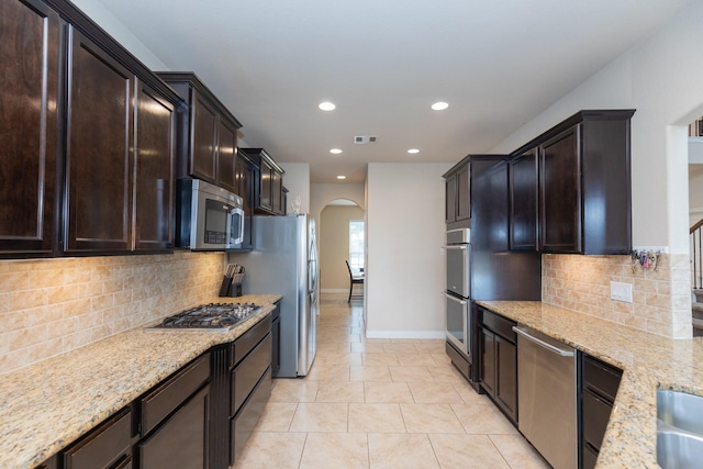 kitchen with light stone counters, light tile patterned floors, backsplash, and appliances with stainless steel finishes