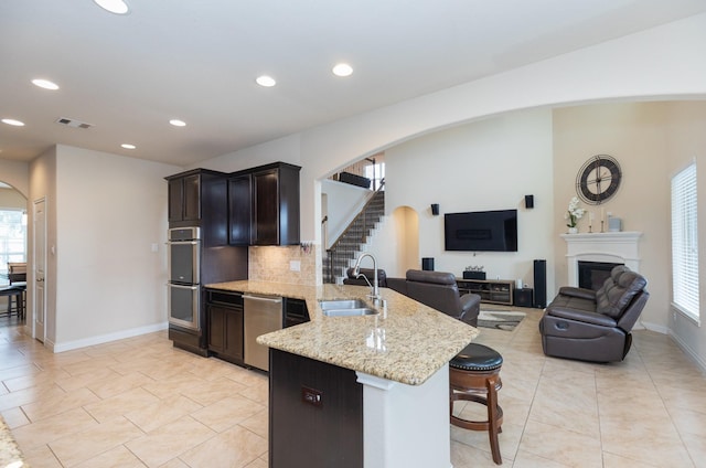 kitchen with sink, light stone counters, a kitchen breakfast bar, kitchen peninsula, and stainless steel appliances