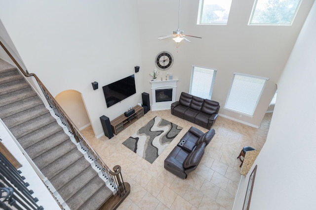 living room with ceiling fan, plenty of natural light, and a towering ceiling