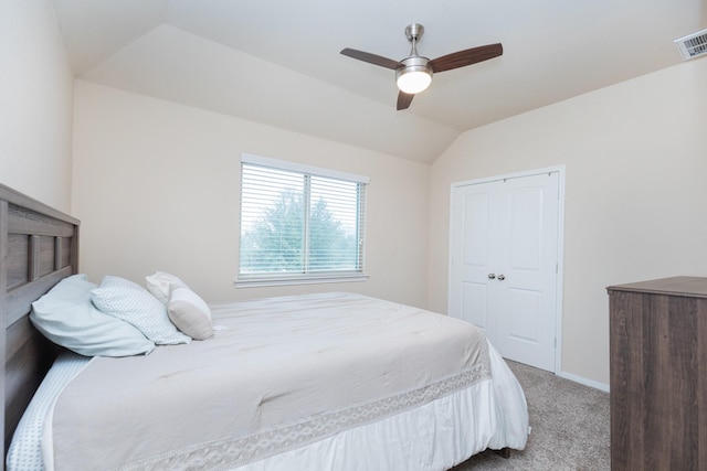 carpeted bedroom with ceiling fan, vaulted ceiling, and a closet