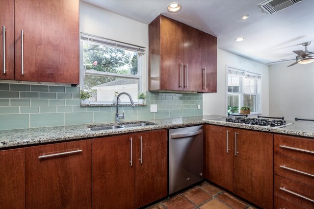 kitchen featuring sink, appliances with stainless steel finishes, ceiling fan, light stone countertops, and backsplash