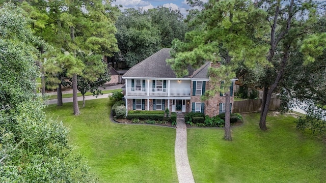 colonial inspired home featuring a balcony and a front lawn