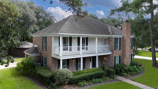 view of front of home with a balcony, central AC unit, and a front lawn