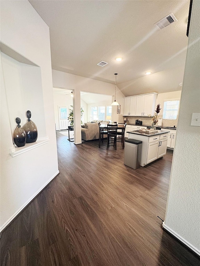 kitchen featuring white cabinetry, decorative light fixtures, vaulted ceiling, and dark hardwood / wood-style floors