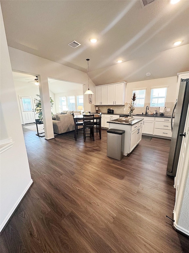 kitchen featuring dark hardwood / wood-style flooring, hanging light fixtures, stainless steel fridge, and white cabinets