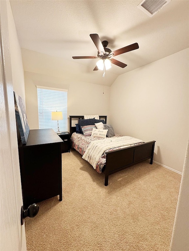 bedroom featuring lofted ceiling, ceiling fan, light colored carpet, and a textured ceiling