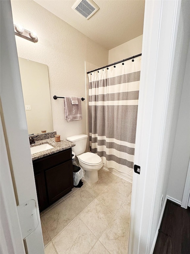 bathroom with vanity, a textured ceiling, and toilet