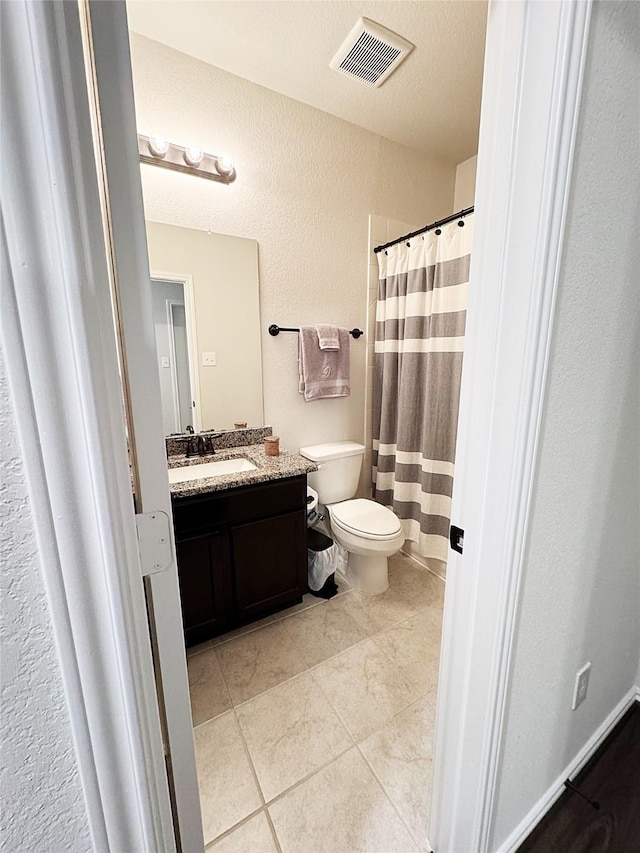 bathroom with tile patterned floors, vanity, toilet, and a textured ceiling