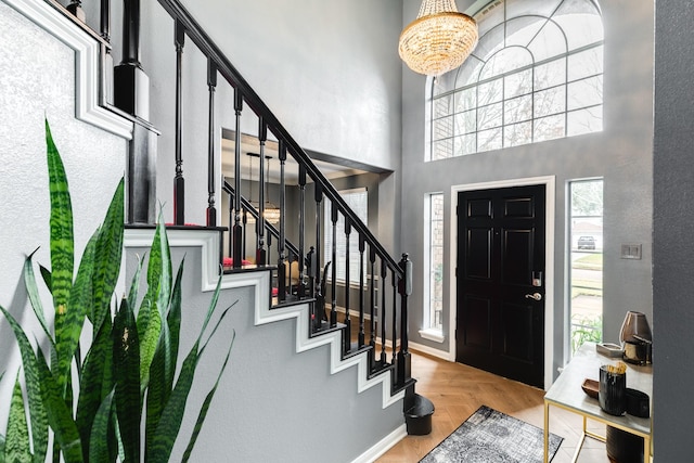 entryway with an inviting chandelier, light parquet flooring, and a high ceiling