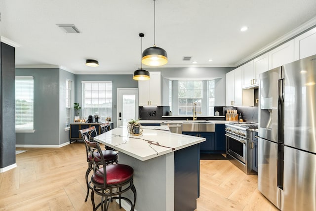 kitchen with appliances with stainless steel finishes, pendant lighting, white cabinetry, light parquet floors, and a center island