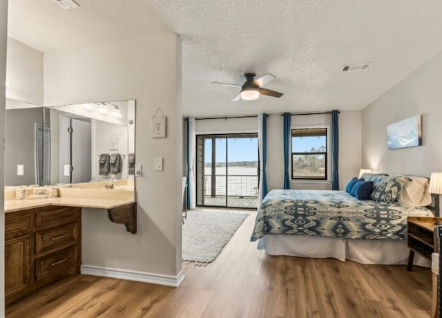 bedroom with ceiling fan, access to outside, light hardwood / wood-style floors, and a textured ceiling