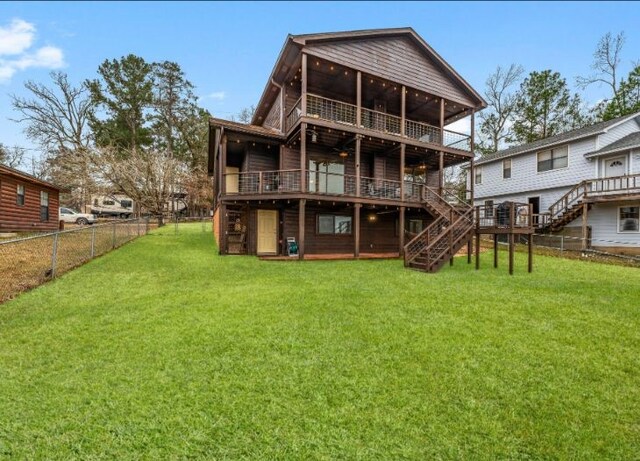 rear view of property with a balcony, a yard, and a deck