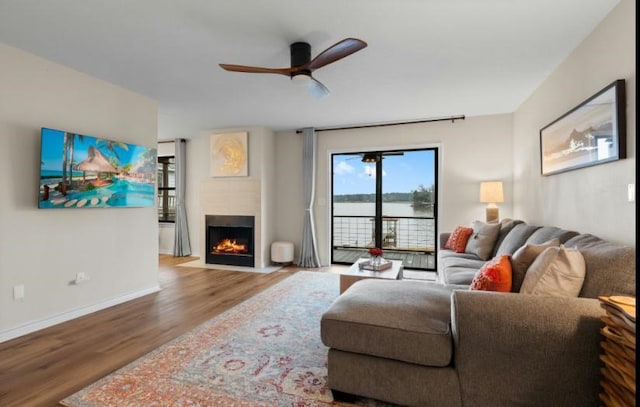 living room with hardwood / wood-style flooring, a water view, and ceiling fan