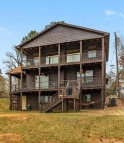 rear view of property featuring central AC unit, a yard, and a deck